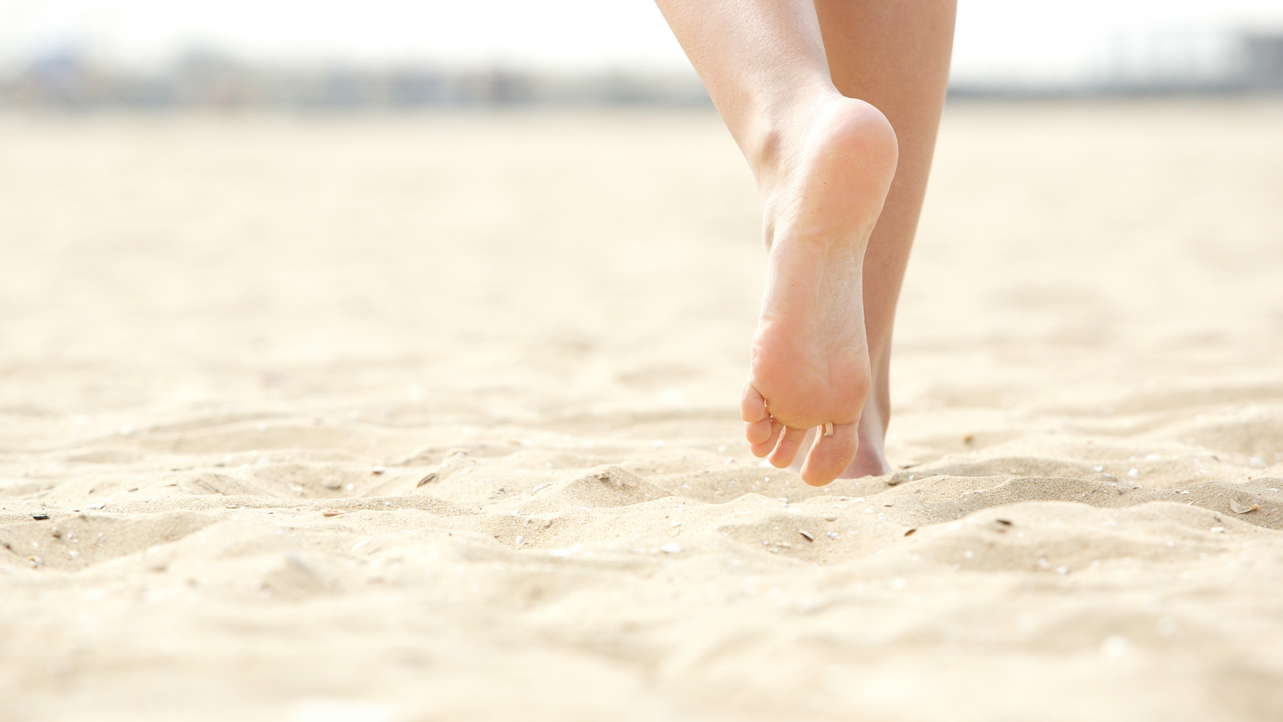 Feet walking barefoot in sand