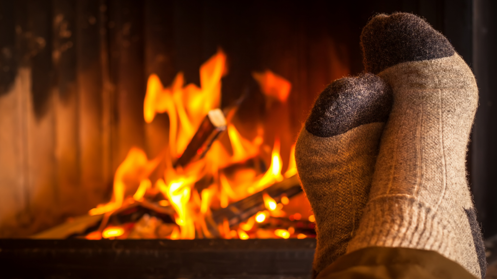 close up of feet in woolen socks, with a fireplace in the background